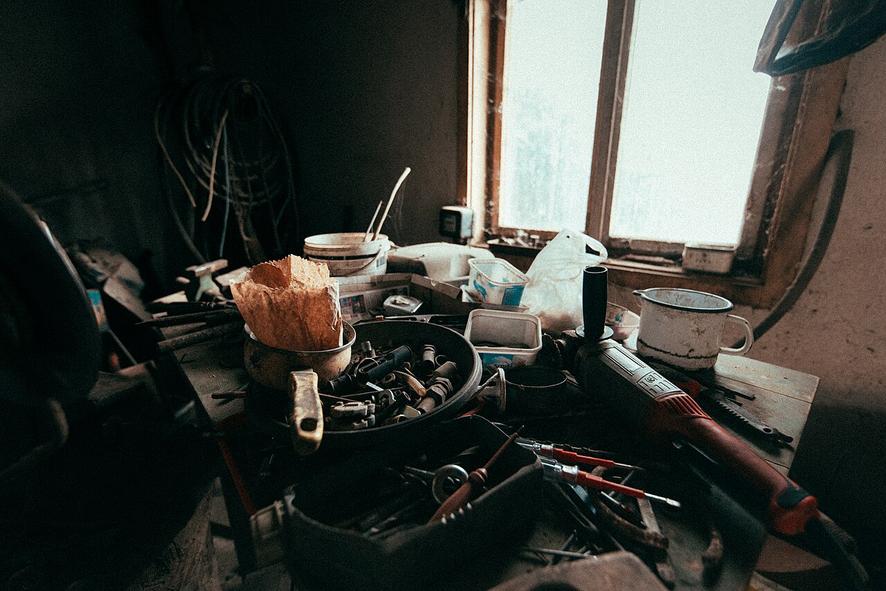 Cluttered workbench in a rustic workshop filled with tools and materials