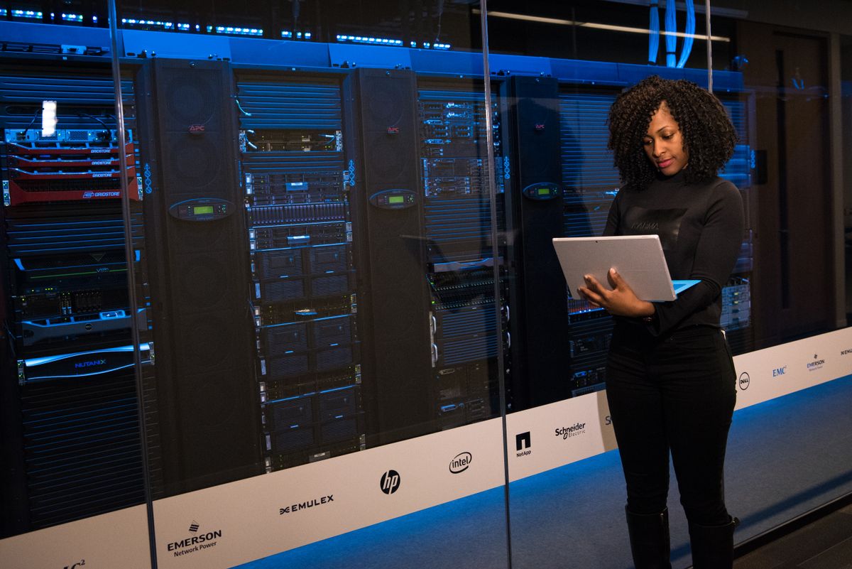 Engineer using a laptop beside server racks
