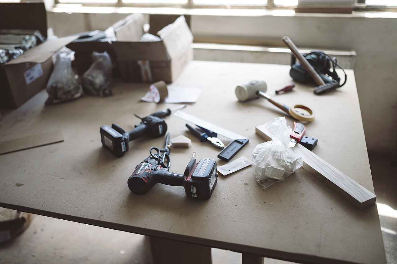 Workbench cluttered with tools, screws, and materials during a DIY project in a bright workshop